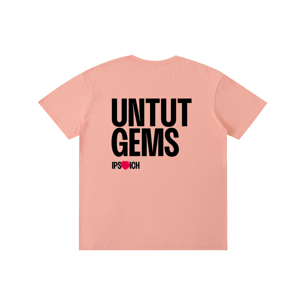 A peach-pink short-sleeve t-shirt shown from the back, featuring the text 'UNTUT GEMS' in bold black letters and 'IP[S]OUCH' in smaller text below with a red heart.